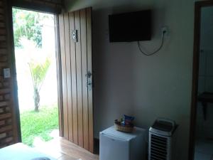 Habitación con nevera y TV en la pared. en Pousada Império estrada Real en Santa Cruz de Minas