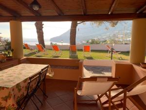 a room with a table and chairs and a view of the ocean at Case Vacanza Cafarella in Malfa