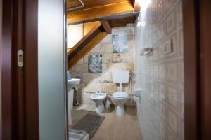 een badkamer met 2 toiletten en een stenen muur bij Casa Alessandra in Augusta