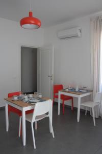 a dining room with two tables and red chairs at Gli olivi in Oliena