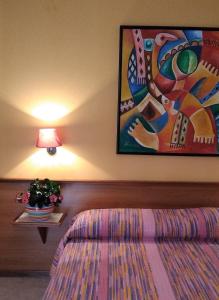1 dormitorio con 1 cama y una pintura en la pared en Villa Romana, en Lignano Sabbiadoro
