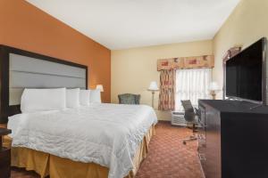a hotel room with a bed and a flat screen tv at Baymont by Wyndham Fayetteville in Fayetteville