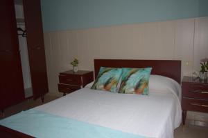 a bedroom with a white bed with two night stands at As Carreiras in Bueu