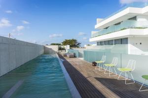 a pool on the roof of a building with chairs at Posia Retreat & Spa UNA Esperienze in San Foca