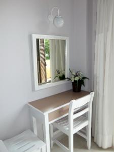 a white desk with a mirror and a chair at Scheria Hotel in Dassia