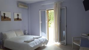 ein weißes Schlafzimmer mit einem Bett und einer Glasschiebetür in der Unterkunft Scheria Hotel in Dassia