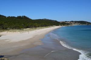 a beach with a group of people in the water at As Carreiras in Bueu