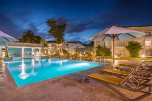 ein Pool in der Nacht mit Stühlen und einem Sonnenschirm in der Unterkunft Emotions by Hodelpa Puerto Plata in San Felipe de Puerto Plata