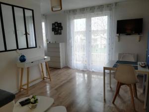 ein Wohnzimmer mit einem großen Fenster und einem Tisch in der Unterkunft Appartement Cosy proche Météo France et Airbus in Toulouse