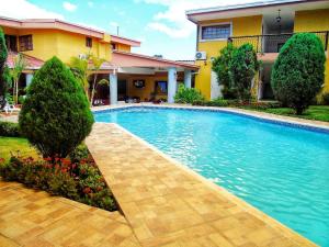 a swimming pool in front of a house at Hotel Los Pinos in Managua