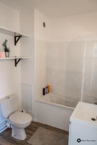 a white bathroom with a toilet and a bath tub at Studio moderne accès plage, piscine et tennis in Cabourg