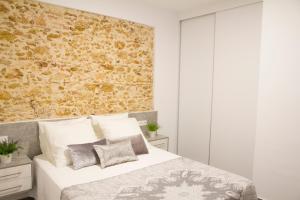 Un dormitorio con una pared de ladrillo y una cama en LUZ DEL FARO, en Cádiz