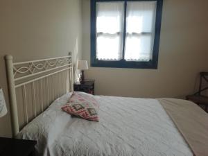 a bedroom with a bed with a pillow and a window at Apartamentos la Marina in Ribadesella