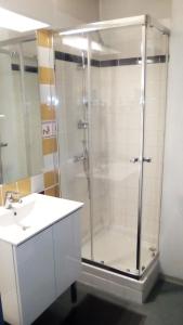uma casa de banho com uma cabina de duche em vidro e um lavatório. em Résidence Mayol em Toulon