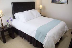 a bedroom with a large white bed with a black headboard at Hotel Nube Nueve in Chignahuapan