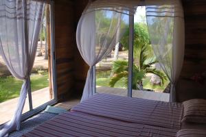 a bedroom with a bed and a large window at Natura luxury lodge in Ouidah +29 photos