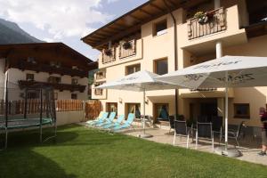 un patio avec des chaises et des parasols en face d'un bâtiment dans l'établissement Appartementhaus zum Zegger, à Neustift im Stubaital