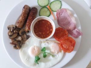 a plate of breakfast food with eggs sausage mushrooms and beans at The Daylesford Guest House in Torquay