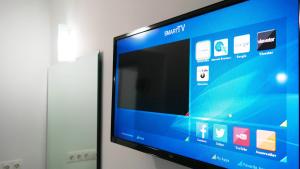 una TV a schermo piatto seduta su un muro di Romanos Beach Villas a Romanu