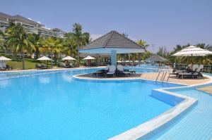 a pool at a resort with chairs and umbrellas at Villa Panda at Sea Links Golf Resort in Mui Ne