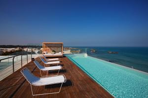 a swimming pool with lounge chairs and the ocean at Posia Retreat & Spa UNA Esperienze in San Foca