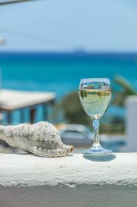una copa de vino sentada en una mesa junto a una concha en Polemis Studios & Apartments en Agia Anna Naxos