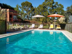 a swimming pool with chairs and umbrellas at Icalma De La Sierra in Tandil