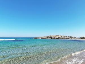 a beach with blue water and rocks in the background at B&B Monte Gruttas in Camisa