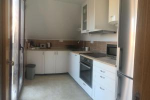 a small kitchen with white cabinets and appliances at Apartamento Ahola in Archena