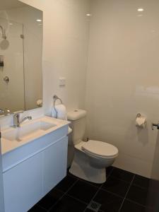 a bathroom with a toilet and a sink and a mirror at Kingsgrove Hotel in Sydney