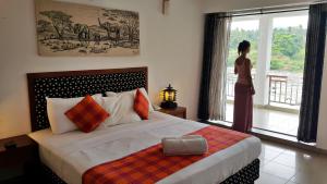 a woman standing in front of a bed in a hotel room at Hotel Pinnalanda in Pinnawala