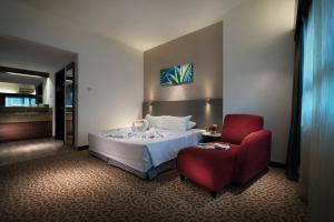 a hotel room with a bed and a red chair at Crown Regency Serviced Suites in Kuala Lumpur