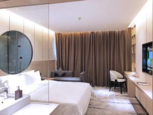 a hotel room with a bed and a mirror at Paco Hotel Guangzhou Baiyun Airport Liantang Metro in Huadu