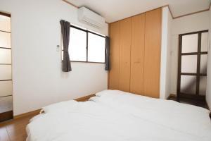 1 dormitorio con 2 camas blancas y ventana en グローバルリゾート宮島 天神ハウス, en Miyajima