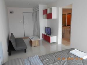 a bedroom with a bed and a chair and a television at The Hug Condo Bangsaen in Bangsaen