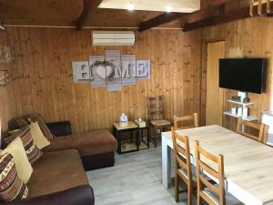 a living room with a table and a couch and a tv at Le Chalet du Lac - Domaine de la Goujonne in Saint-Sauveur-lès-Bray