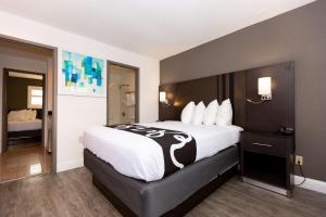 una habitación de hotel con una cama grande con sábanas blancas en SureStay Hotel by Best Western Seaside Monterey, en Seaside