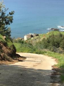 een onverharde weg met een gebouw op een heuvel naast de oceaan bij Beach Villa Pantheon in Pomos