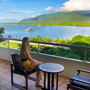 a woman sitting on a bench in front of a lake at Pullman Reef Hotel Casino in Cairns