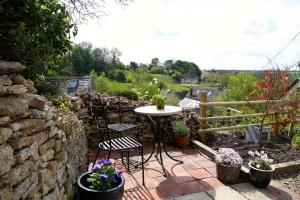 een patio met een tafel en stoelen en een stenen muur bij Hope Cottage in Stroud +7 foto's