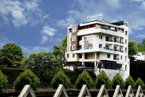 un edificio bianco con alberi di fronte di Comfort Inn Benares a Varanasi