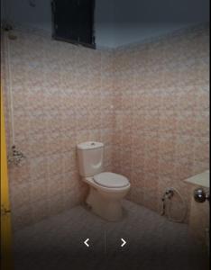 a bathroom with a toilet in a tiled room at Holiday Inn Guest House in Kalar Goth