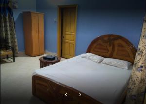 a bedroom with a large bed with a wooden headboard at Holiday Inn Guest House in Kalar Goth