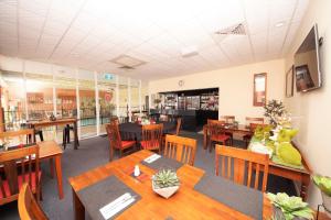 a restaurant with wooden tables and chairs and a cafeteria at Parkside Motel Ayr in Ayr