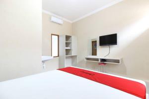 um quarto branco com uma cama e uma televisão em RedDoorz near Balekambang City Park em Surakarta