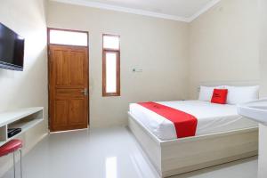 um quarto branco com uma cama e um lavatório em RedDoorz near Balekambang City Park em Surakarta