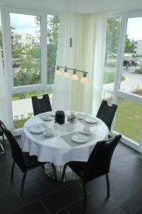 mesa de comedor con sillas y mantel blanco en Ferienwohnung Küstenzauber 20, en Großenbrode