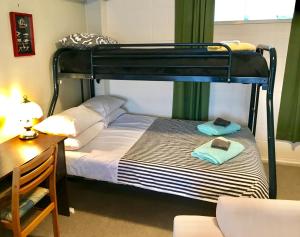 Perfect Base in the Bay Of Islands في Opua: غرفة نوم مع سرير بطابقين مع مكتب وكرسي
