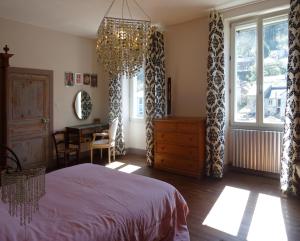 1 dormitorio con cama y lámpara de araña en Les Trois Hiboux, en Crespin