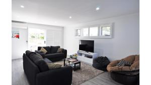 a living room with two couches and a flat screen tv at FANTASEA - FREE FOXTEL in Inverloch